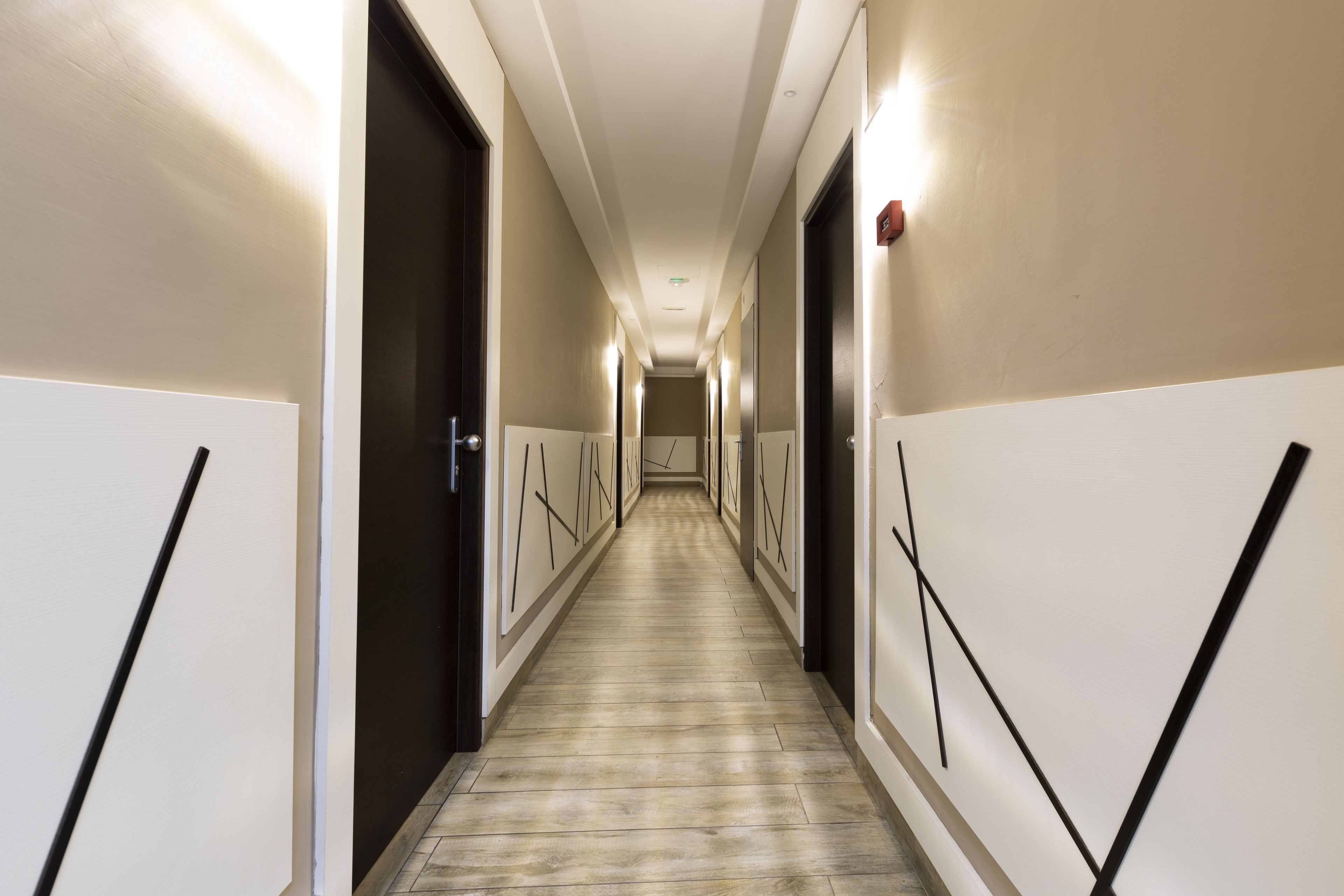 A long, narrow hallway with doors on both sides, leading to individual rooms.