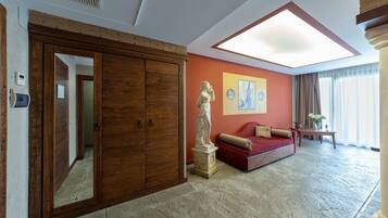 Um quarto espaçoso com um guarda-roupa de madeira grande, um sofá vermelho, uma estátua e um claraboia.