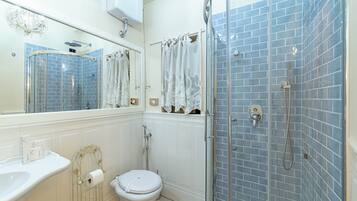 A bathroom with a white toilet, a sink, a shower with a glass door, and blue-tiled walls.