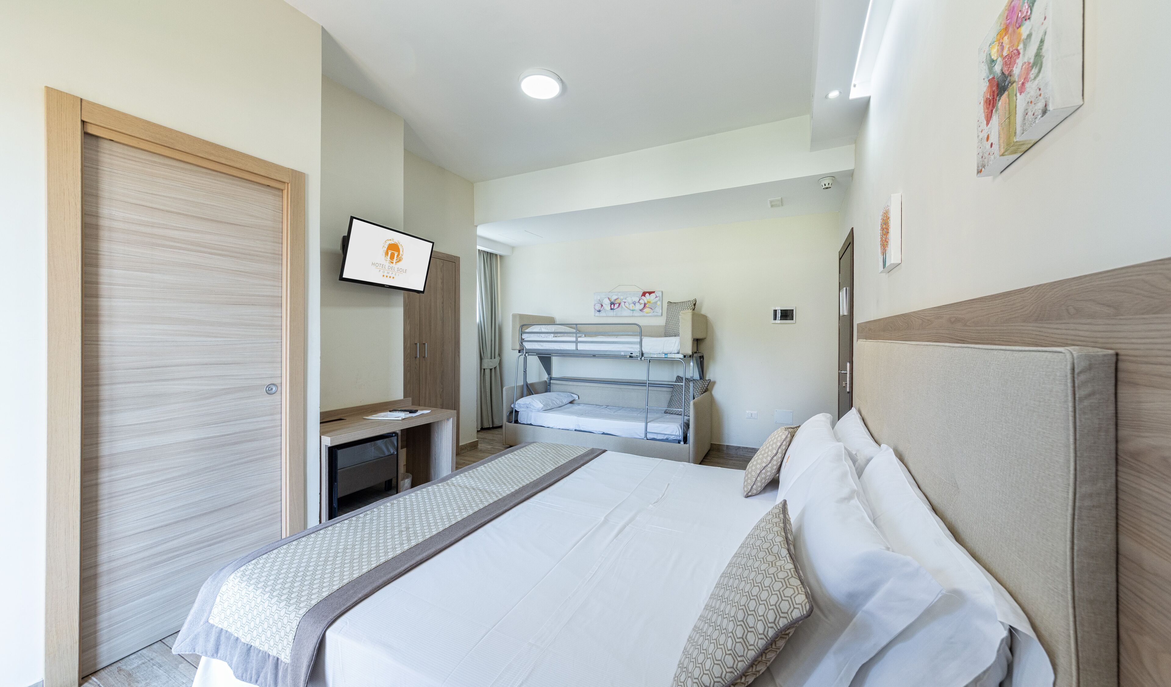 A hotel room with a bed, a desk, a TV, and a wardrobe.