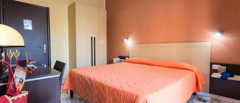 Una habitación de hotel con una cama, un escritorio, una silla, una lámpara y una puerta.
