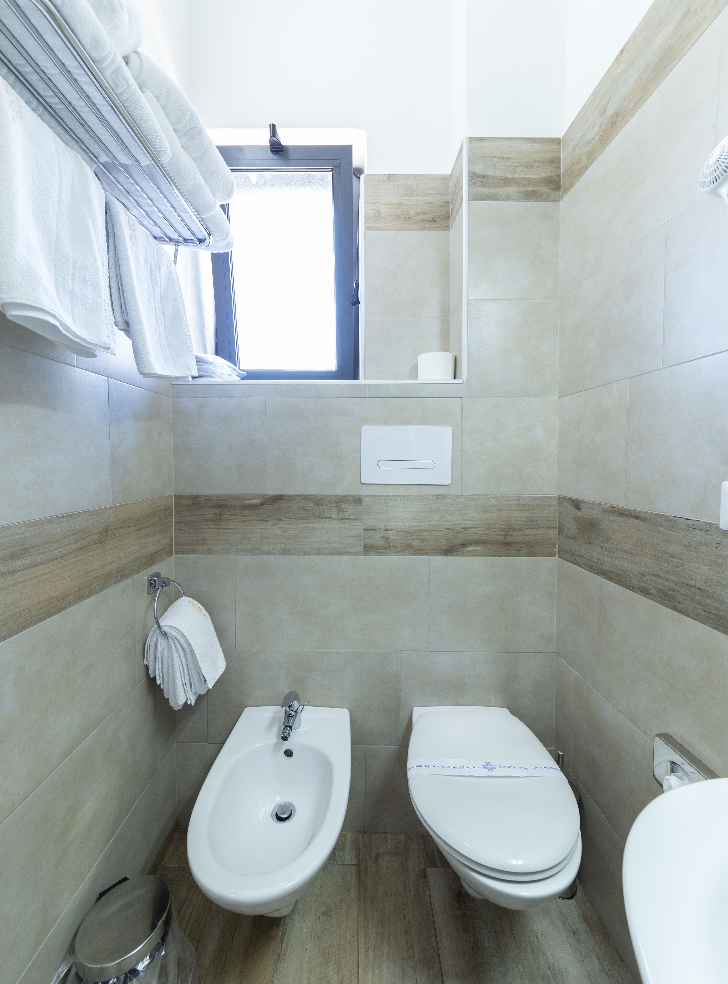 Un baño moderno con bidé, inodoro y perchero para toallas.