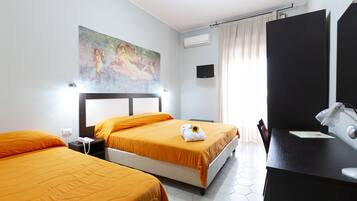 Quarto de hotel com duas camas, uma escrivaninha, uma cadeira, um quadro na parede e uma janela com cortinas.