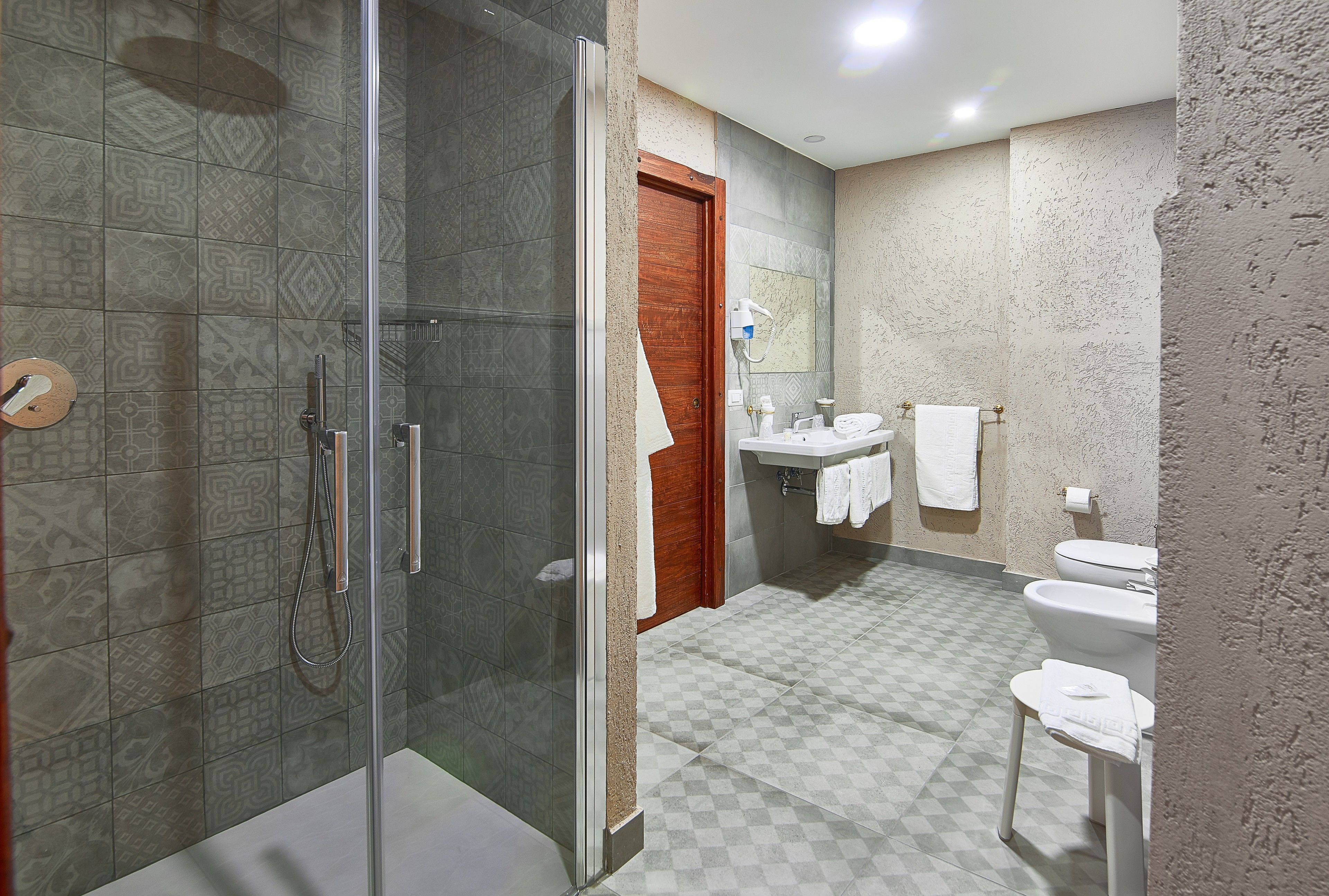 Un baño con ducha de vidrio, una puerta de madera, un lavamanos y un inodoro.