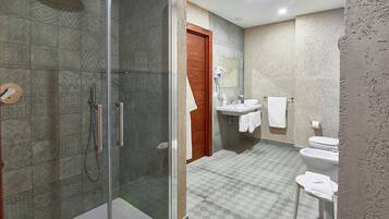 A bathroom with a glass-enclosed shower, a wooden door, a sink, and a toilet.