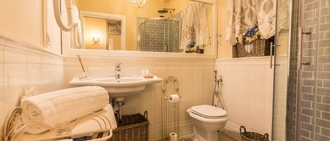A bathroom with a sink, toilet, and shower. There are towels and baskets on the floor.