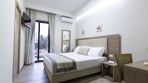 Een moderne hotelkamer met een groot bed, een bureau en een aan de muur bevestigde televisie.