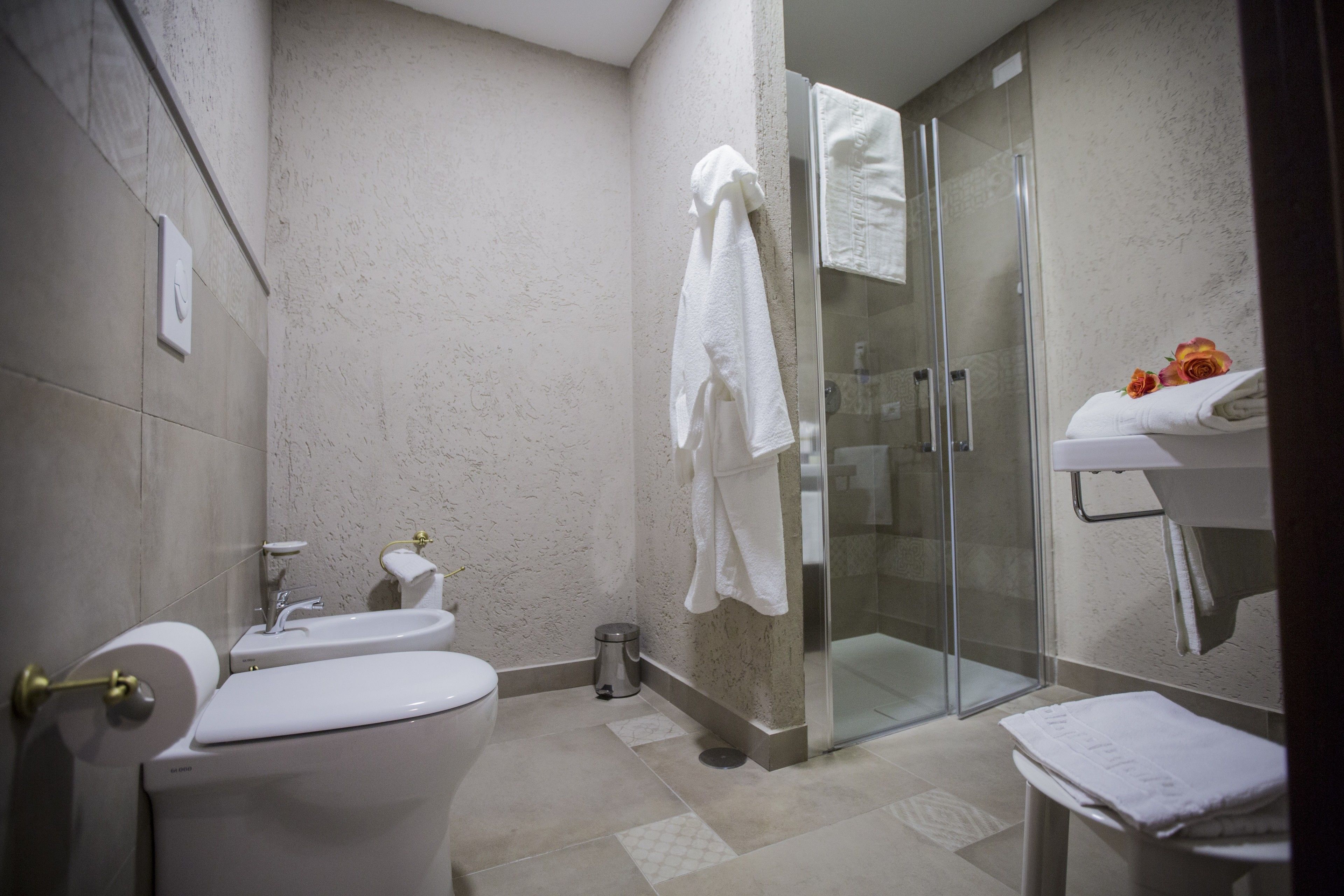 A bathroom with a toilet, sink, and glass shower enclosure.