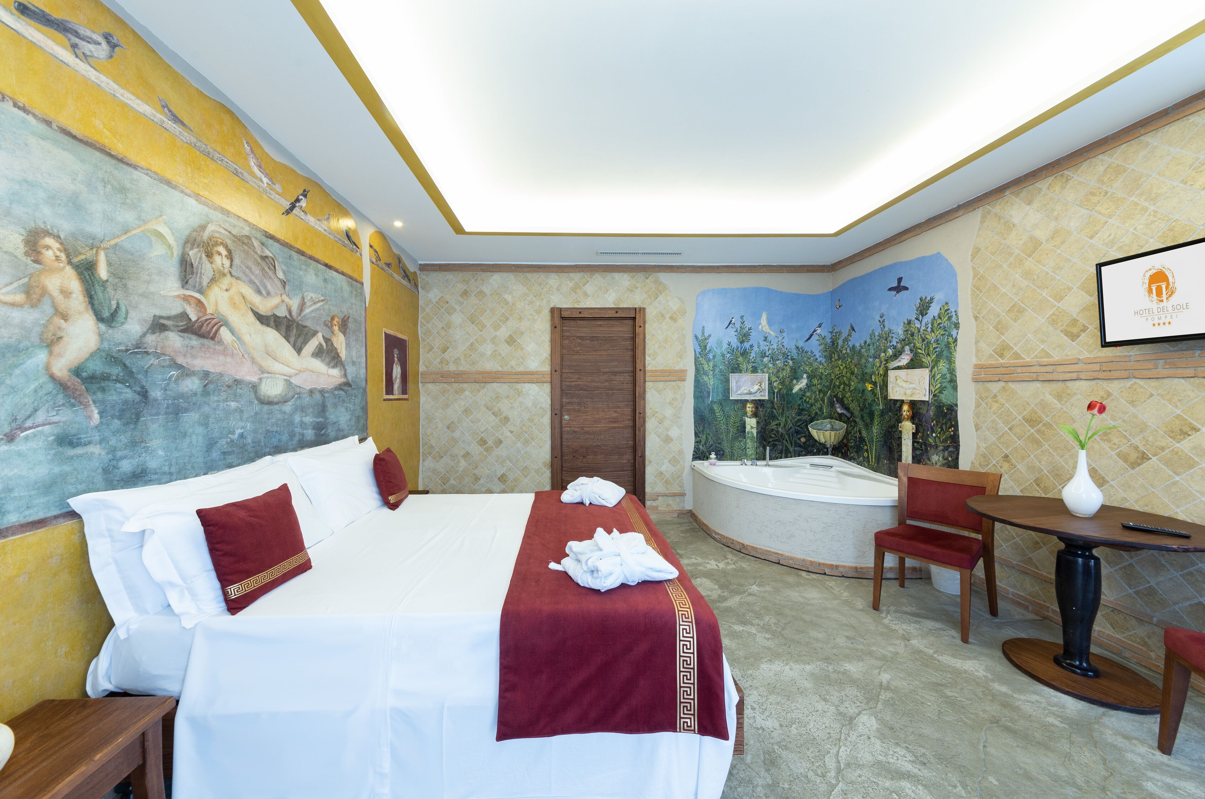 A hotel room with a bed, a desk, a chair, a bathtub, and a mural on the wall.
