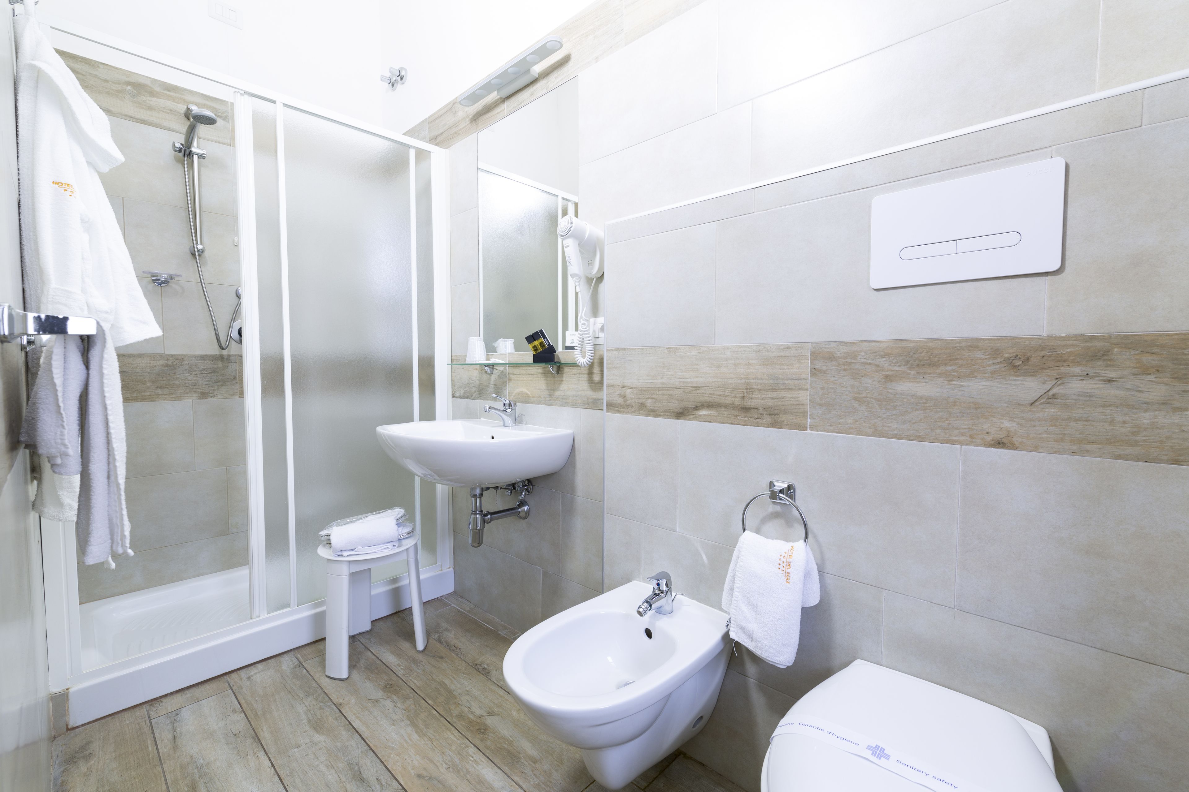 A modern bathroom with a glass-enclosed shower, a sink, a bidet, and a toilet.