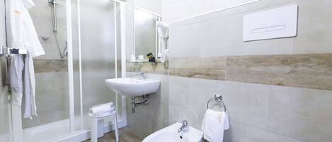 A modern bathroom with a glass-enclosed shower, a sink, a bidet, and a toilet.
