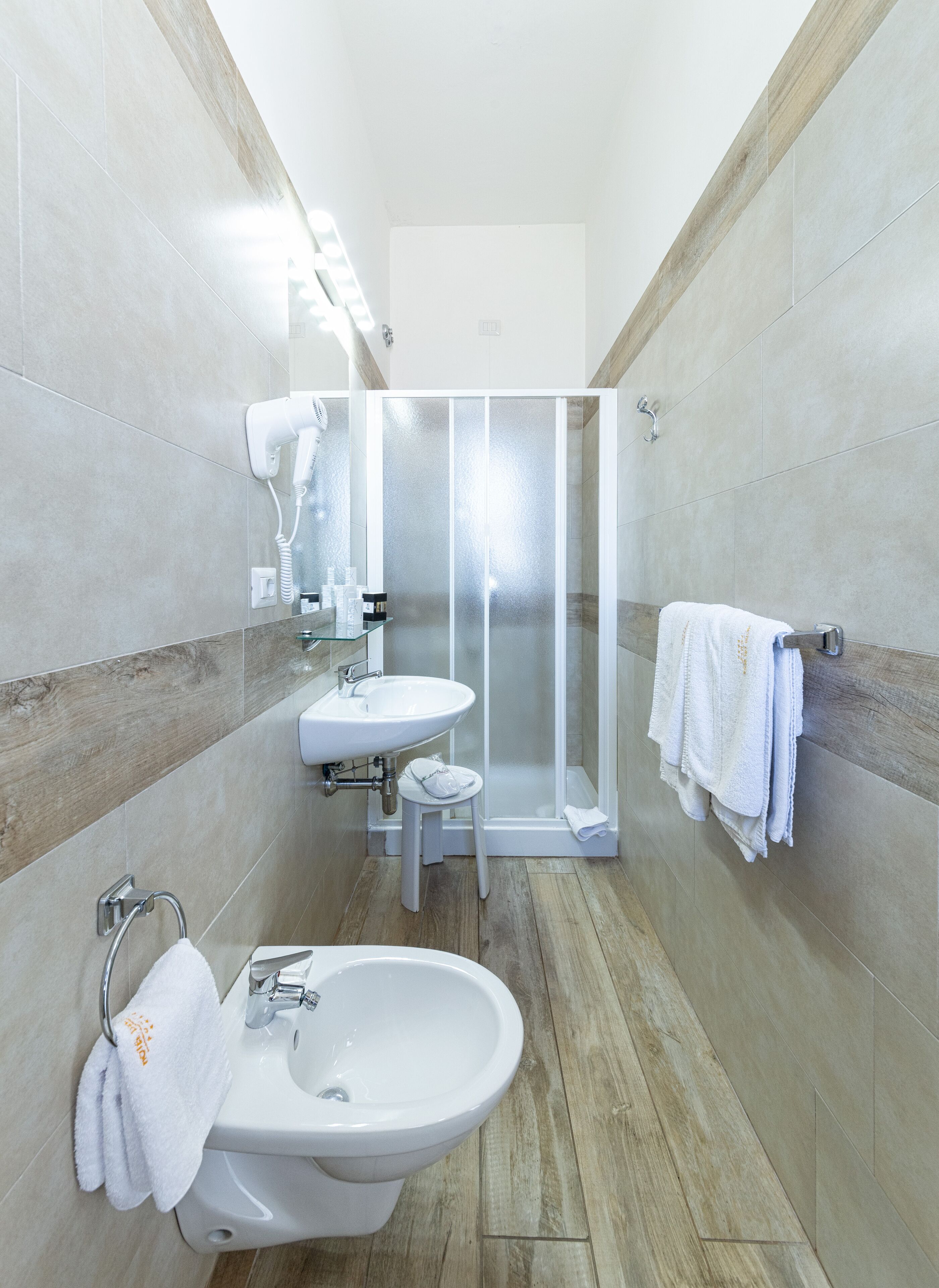 A modern bathroom with a sink, bidet, and glass-enclosed shower.