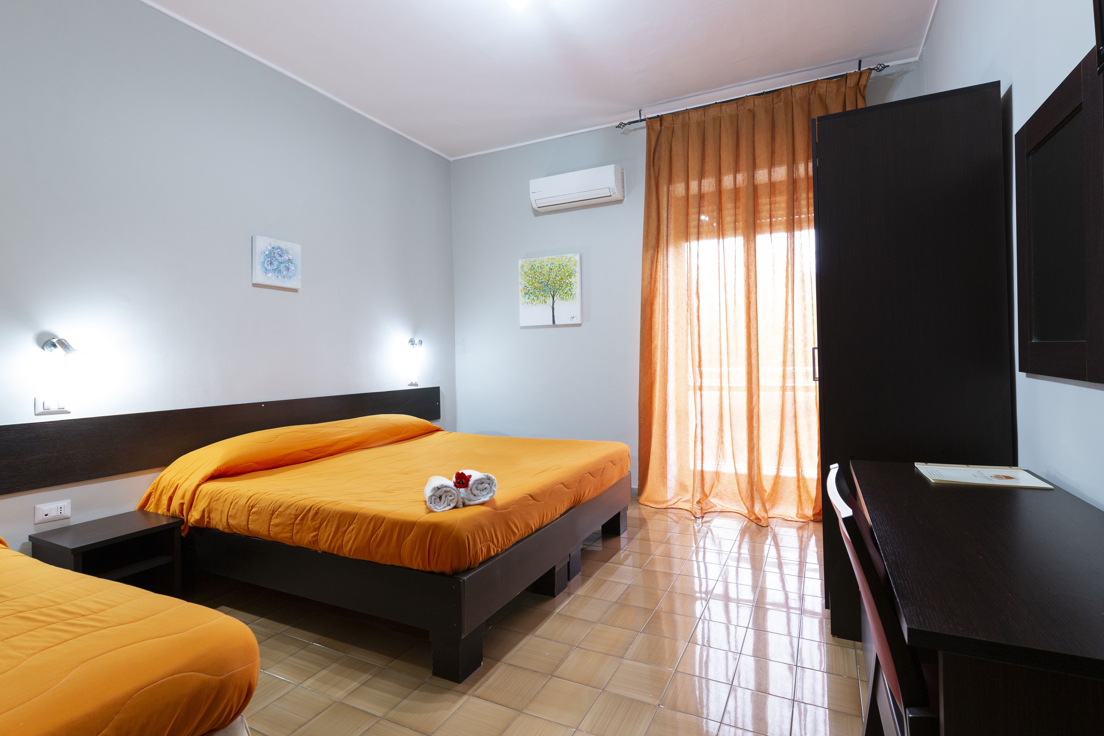 A hotel room with two beds, a flat-screen TV, and a desk.
