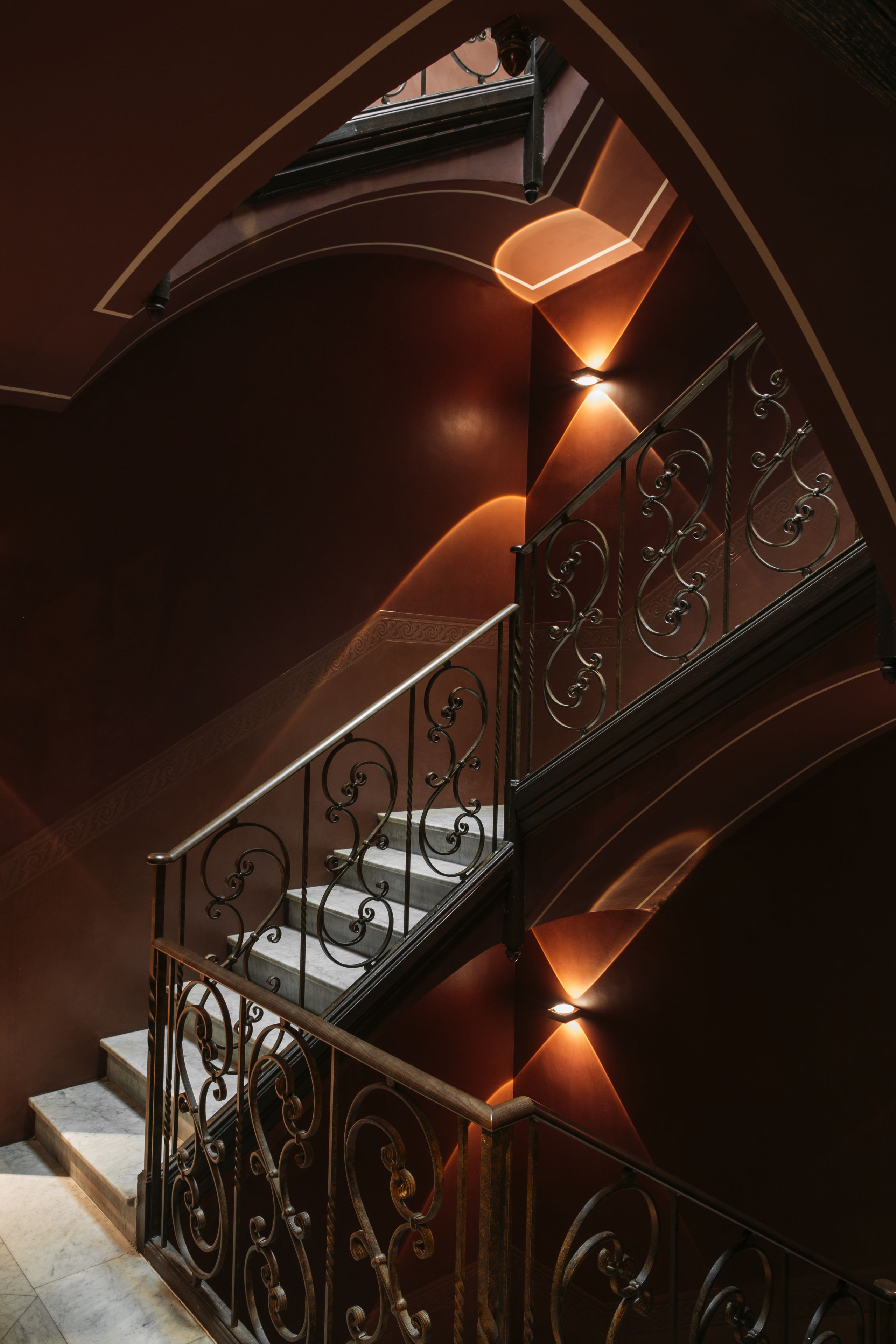 Un magnifique escalier avec des rampes en métal ouvragé et un éclairage chaleureux.