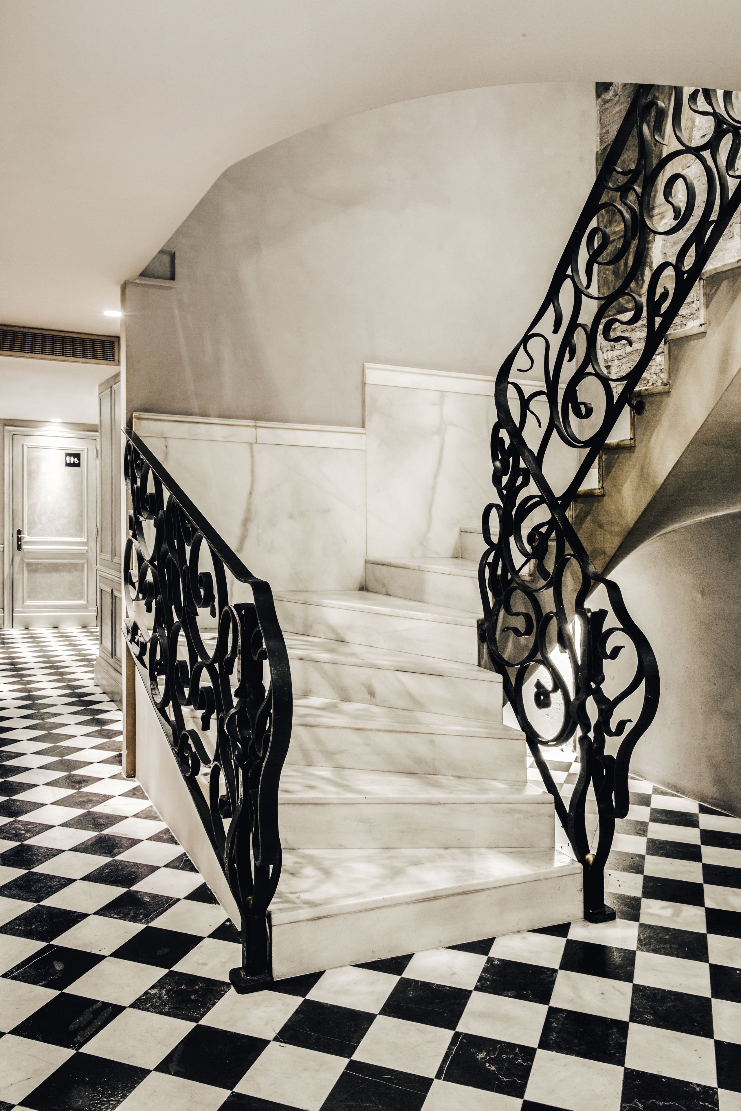 Un escalier avec une rampe en métal noir et un sol à carreaux.