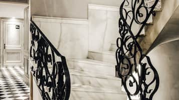 Un escalier avec une rampe en métal noir et un sol à carreaux.
