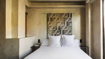 A hotel room with a large bed, a patterned headboard, and a nightstand with a lamp.