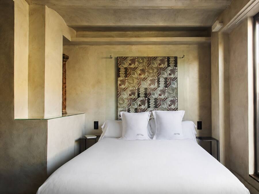 Une chambre d’hôtel avec un grand lit, une tête de lit à motifs et une table de chevet avec une lampe.