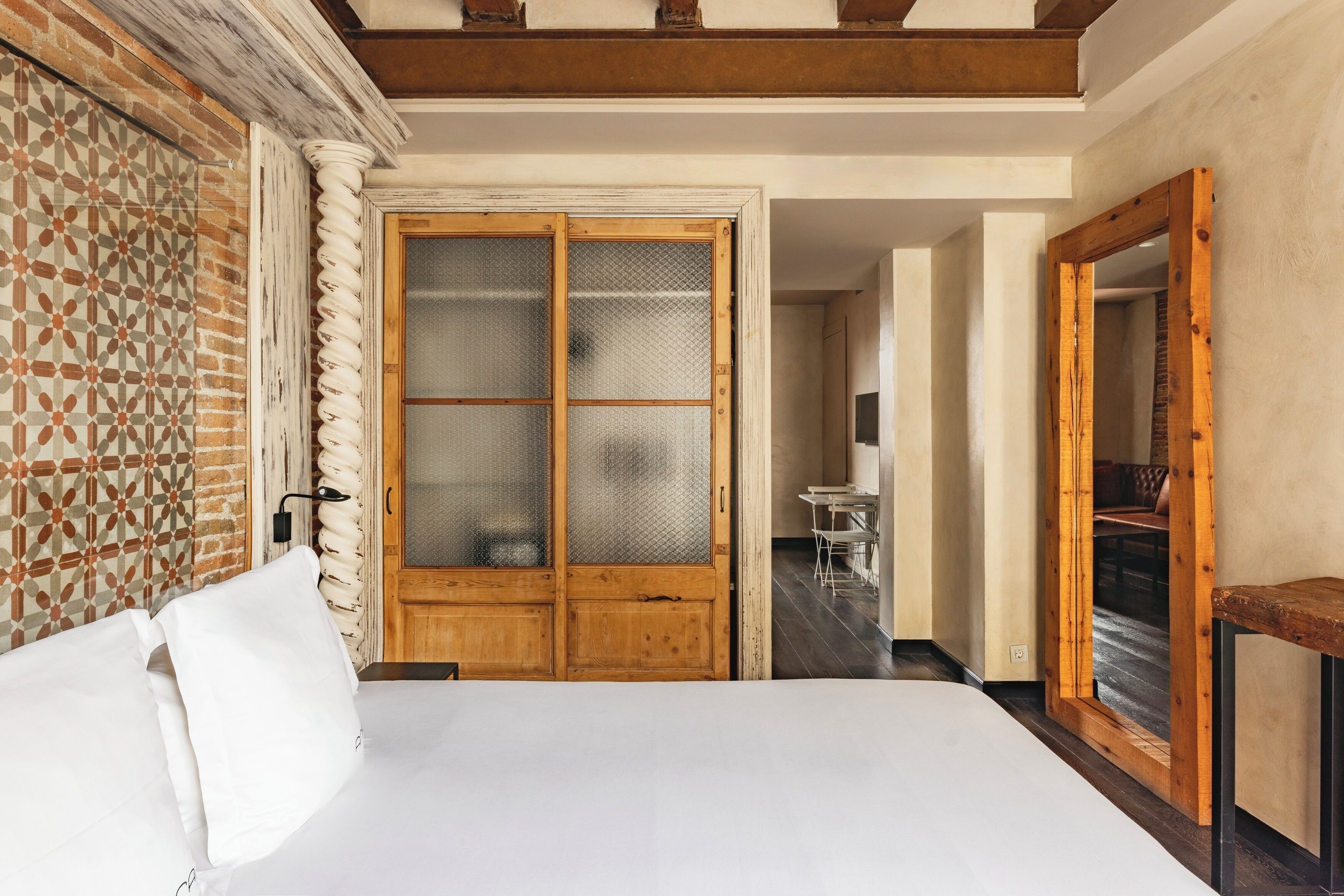 A bedroom with a bed, a wooden wardrobe, and a mirror.