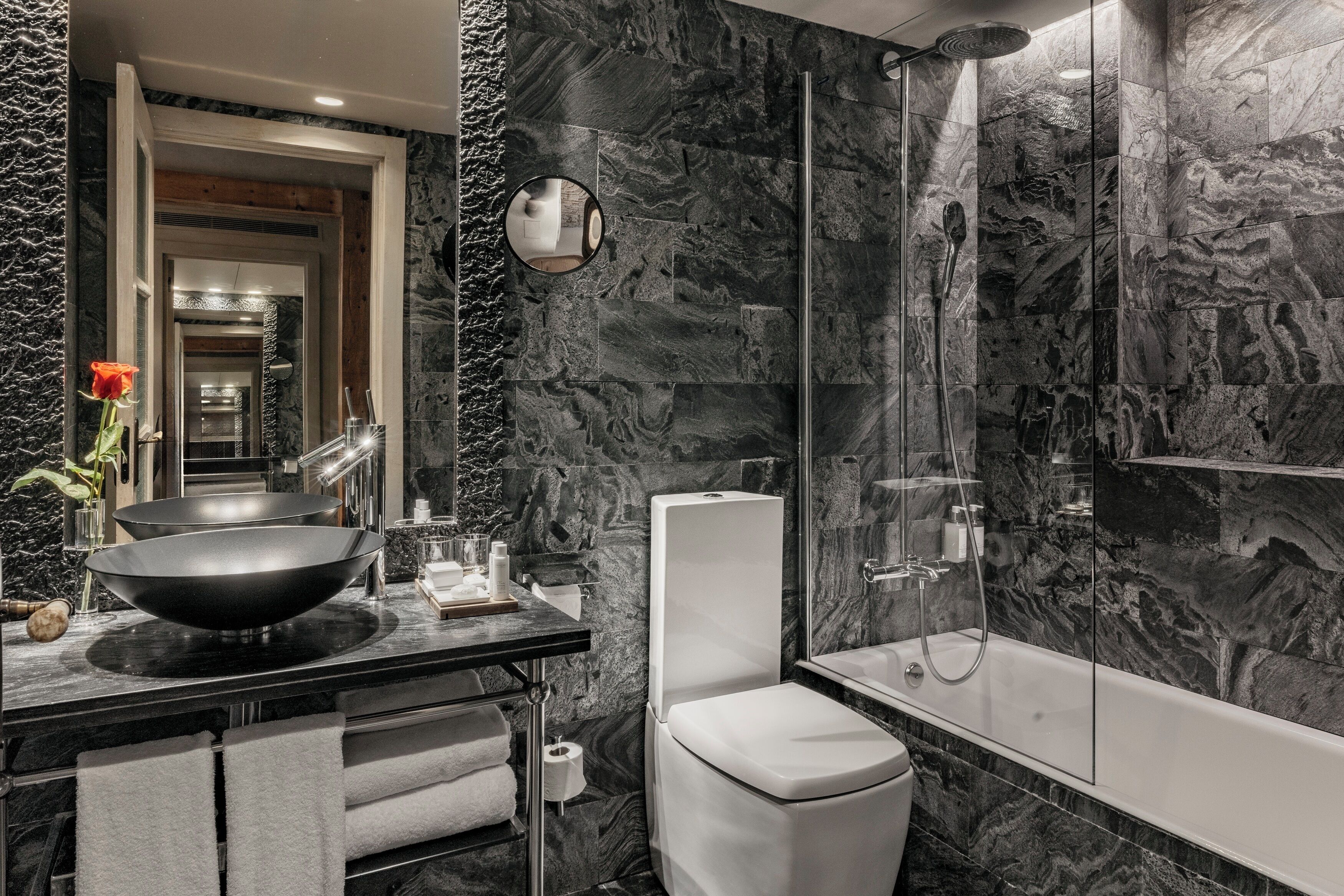 A modern bathroom with a black sink, white toilet, and a glass-enclosed shower.