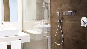 A modern bathroom with a glass-enclosed shower, a white sink, and a large mirror.