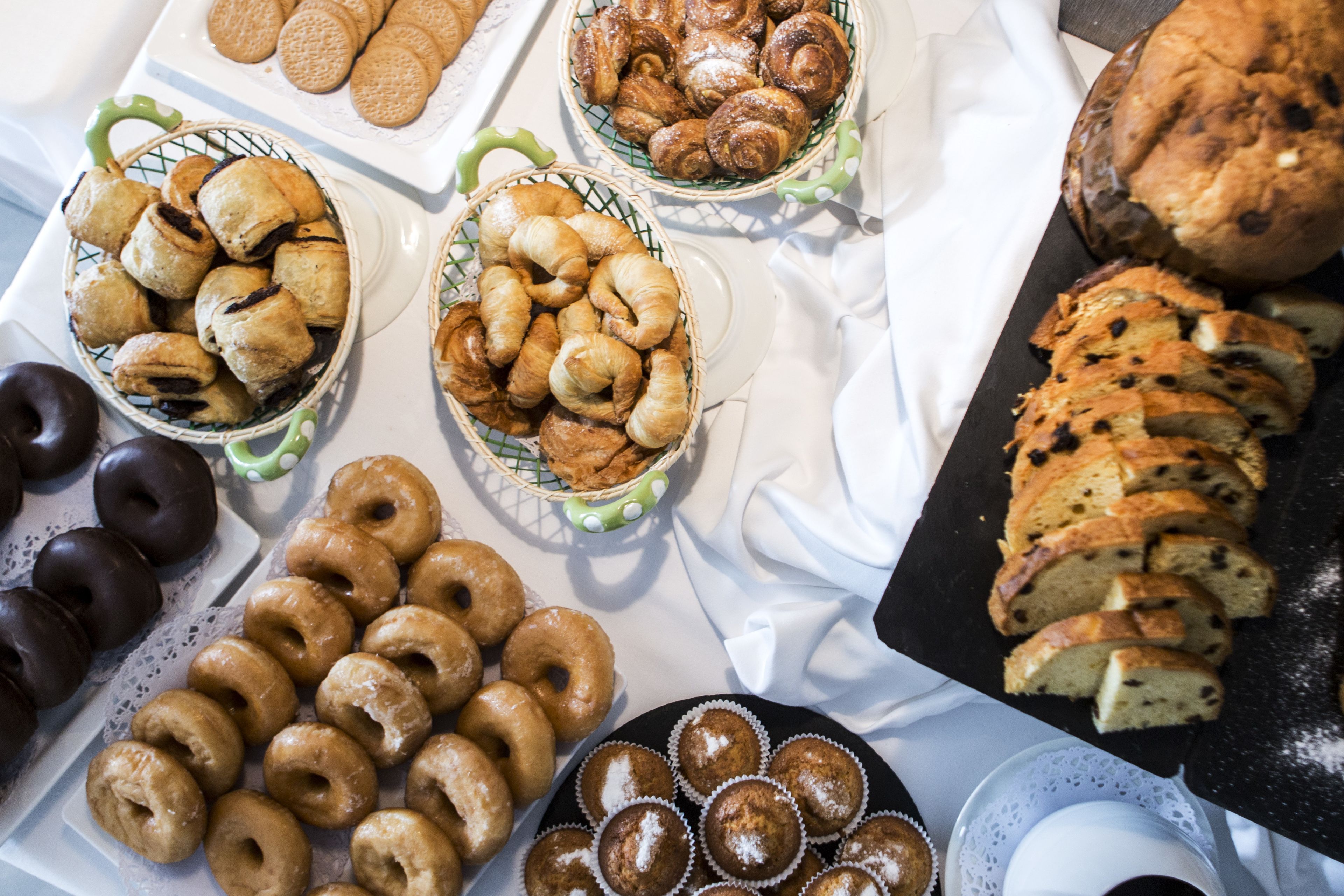 A table with various baked goods including pastries, donuts, and bread.