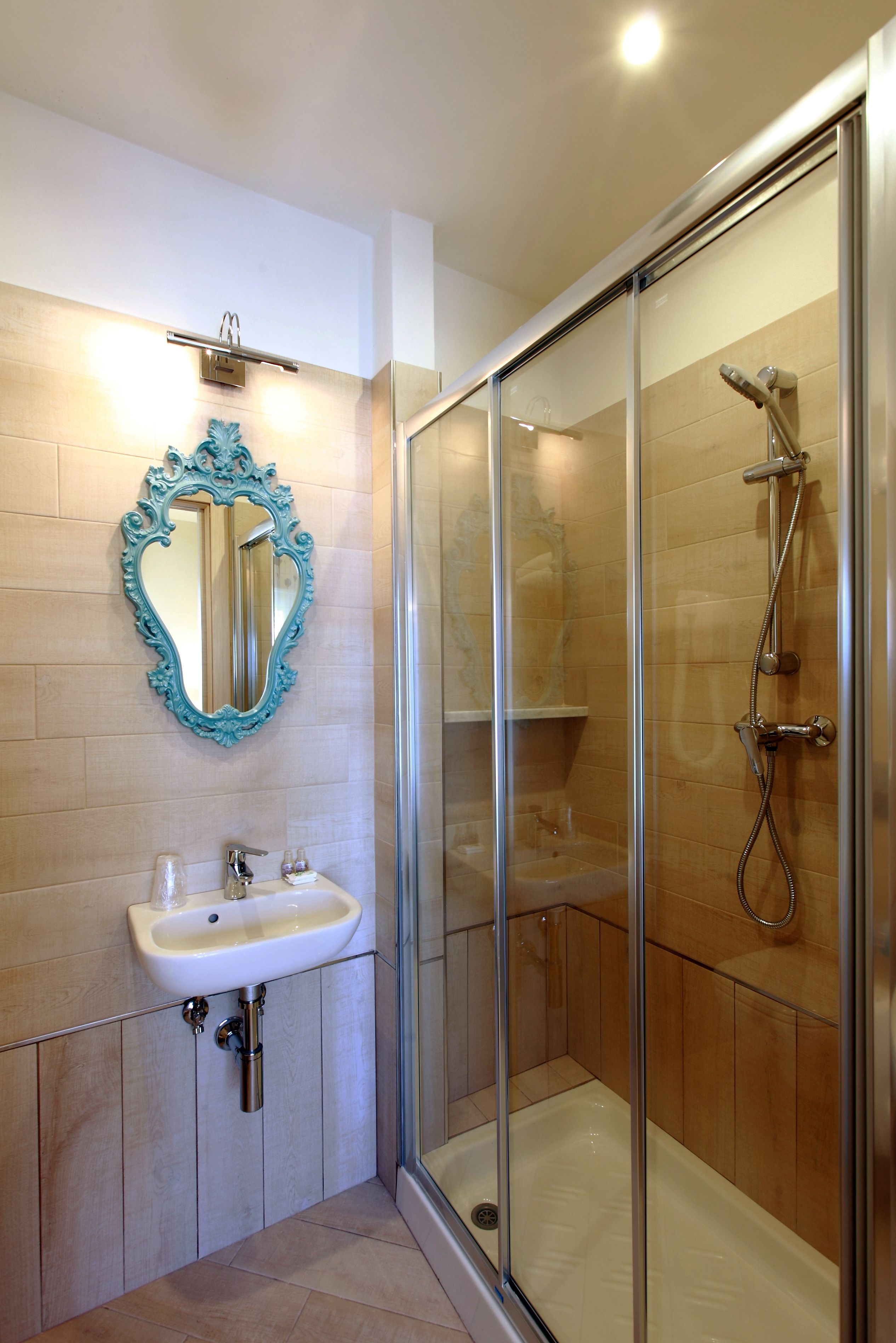 A modern bathroom with a glass-enclosed shower, a white sink, and a decorative mirror.