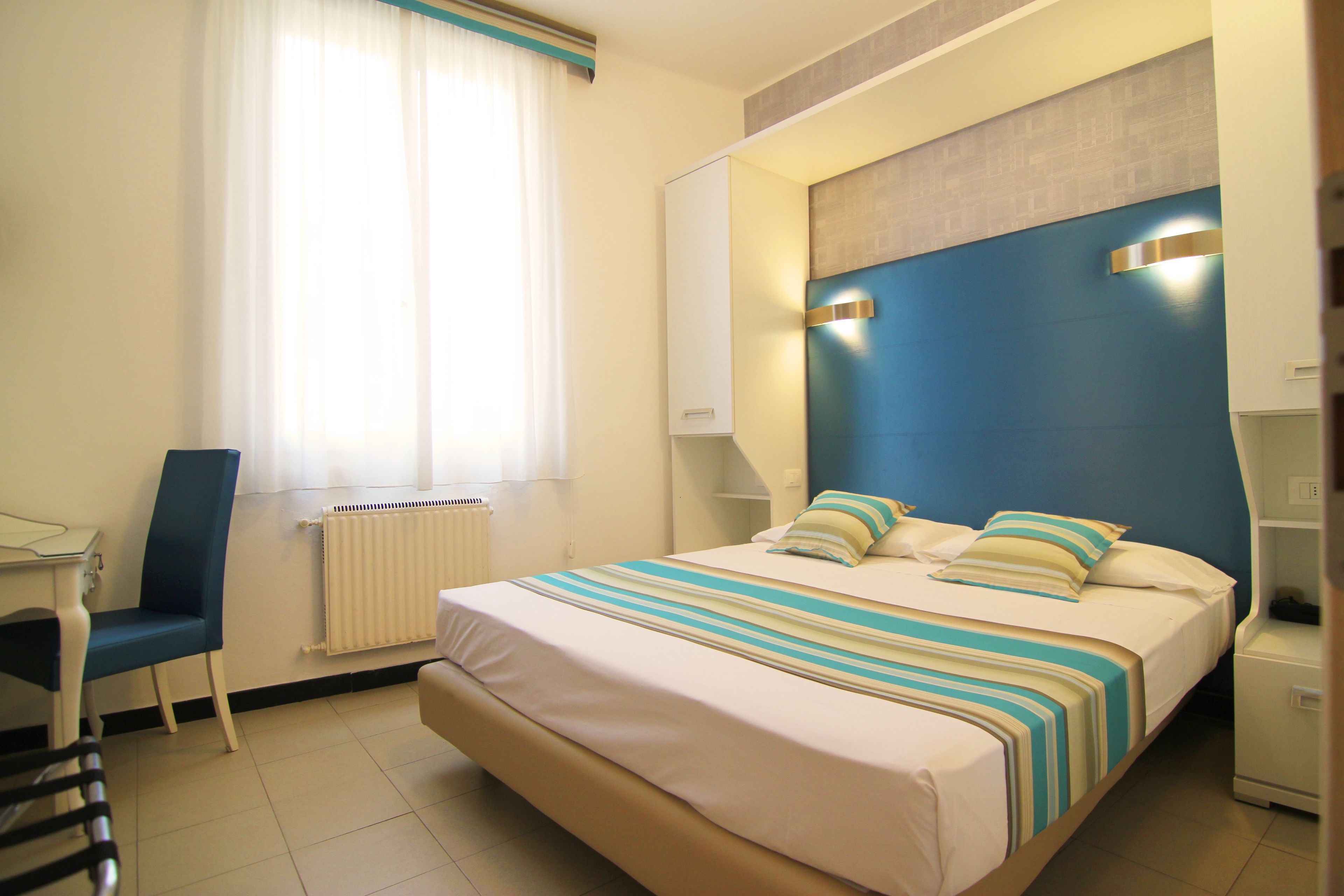 Una habitación de hotel con una cama grande, una silla, un escritorio y una ventana con cortinas.