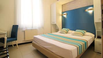 Una habitación de hotel con una cama grande, una silla, un escritorio y una ventana con cortinas.