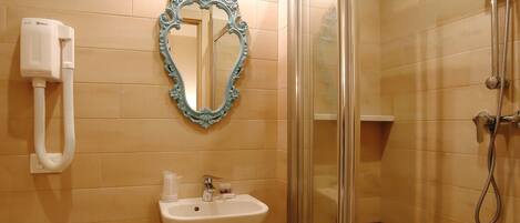 A bathroom with a toilet, sink, mirror, and shower.