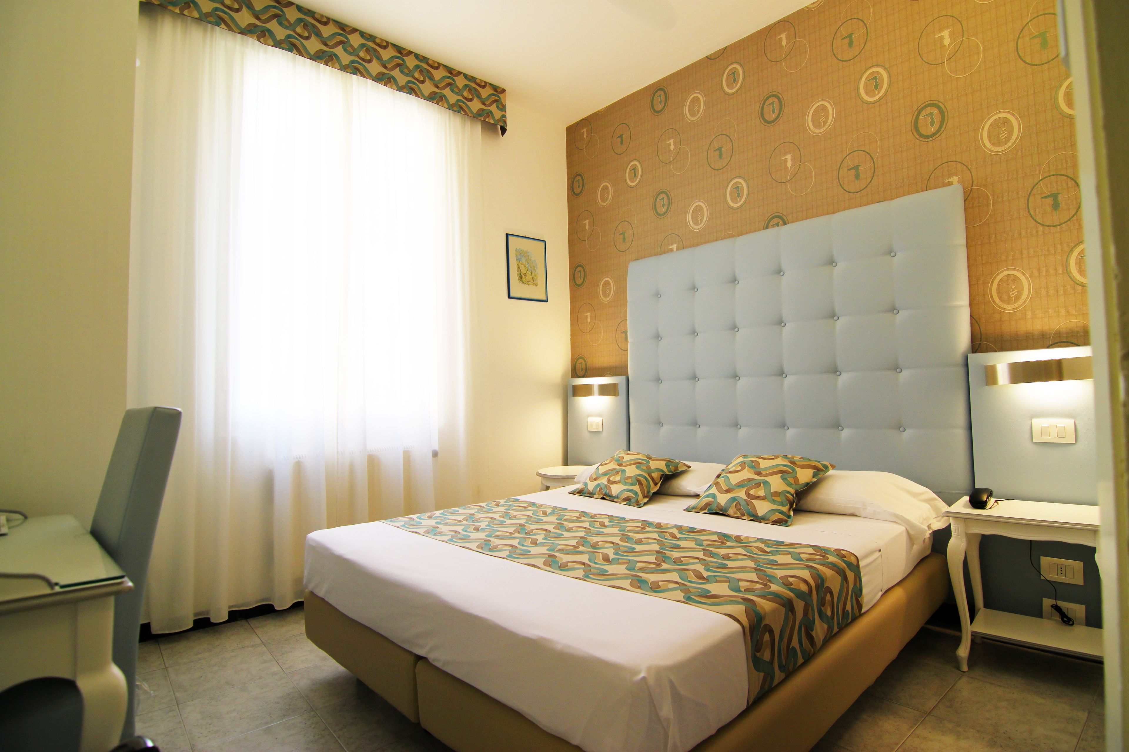 A hotel room with a large bed, a desk, and a chair.