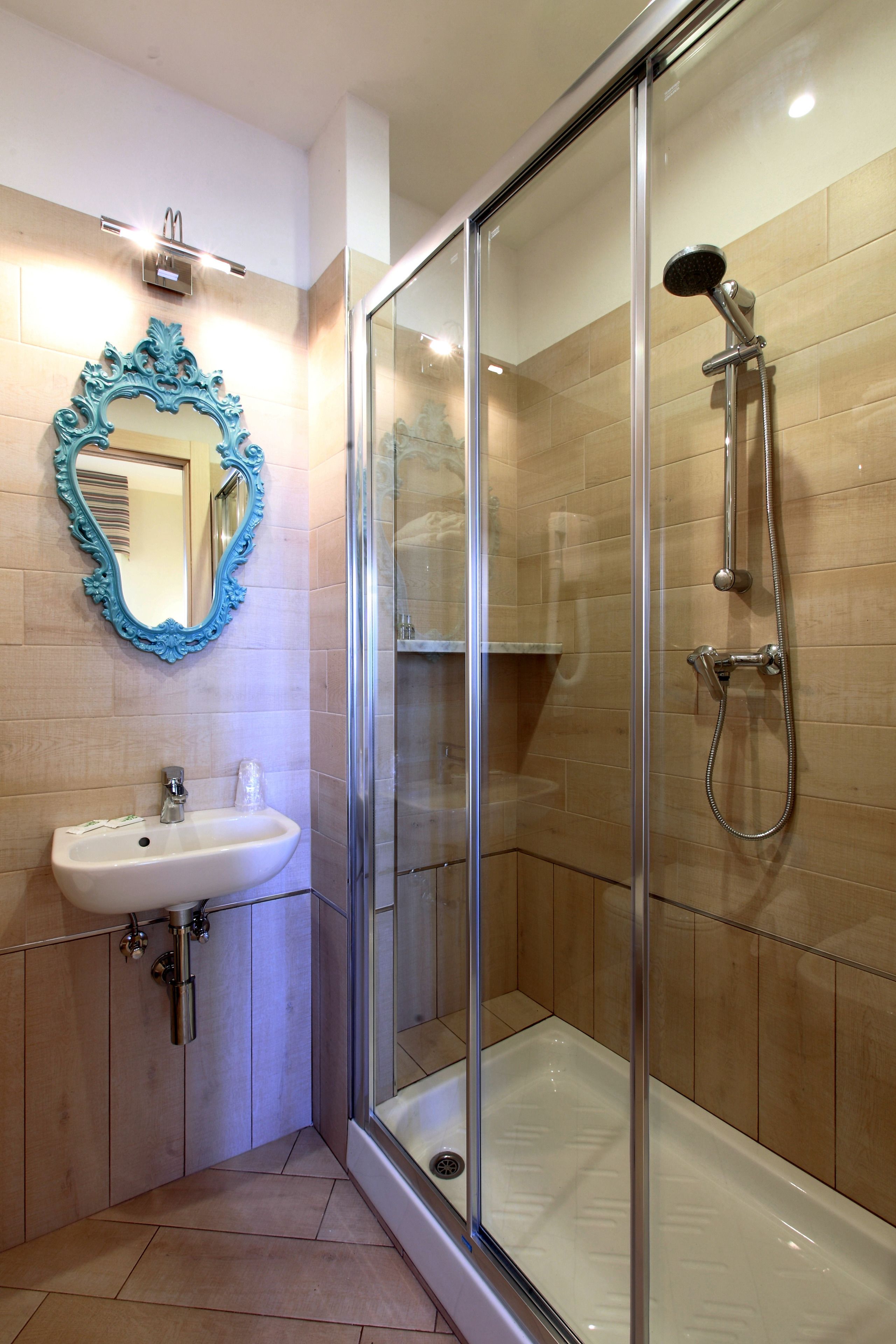 A modern bathroom with a glass-enclosed shower, a white sink, and a decorative mirror.