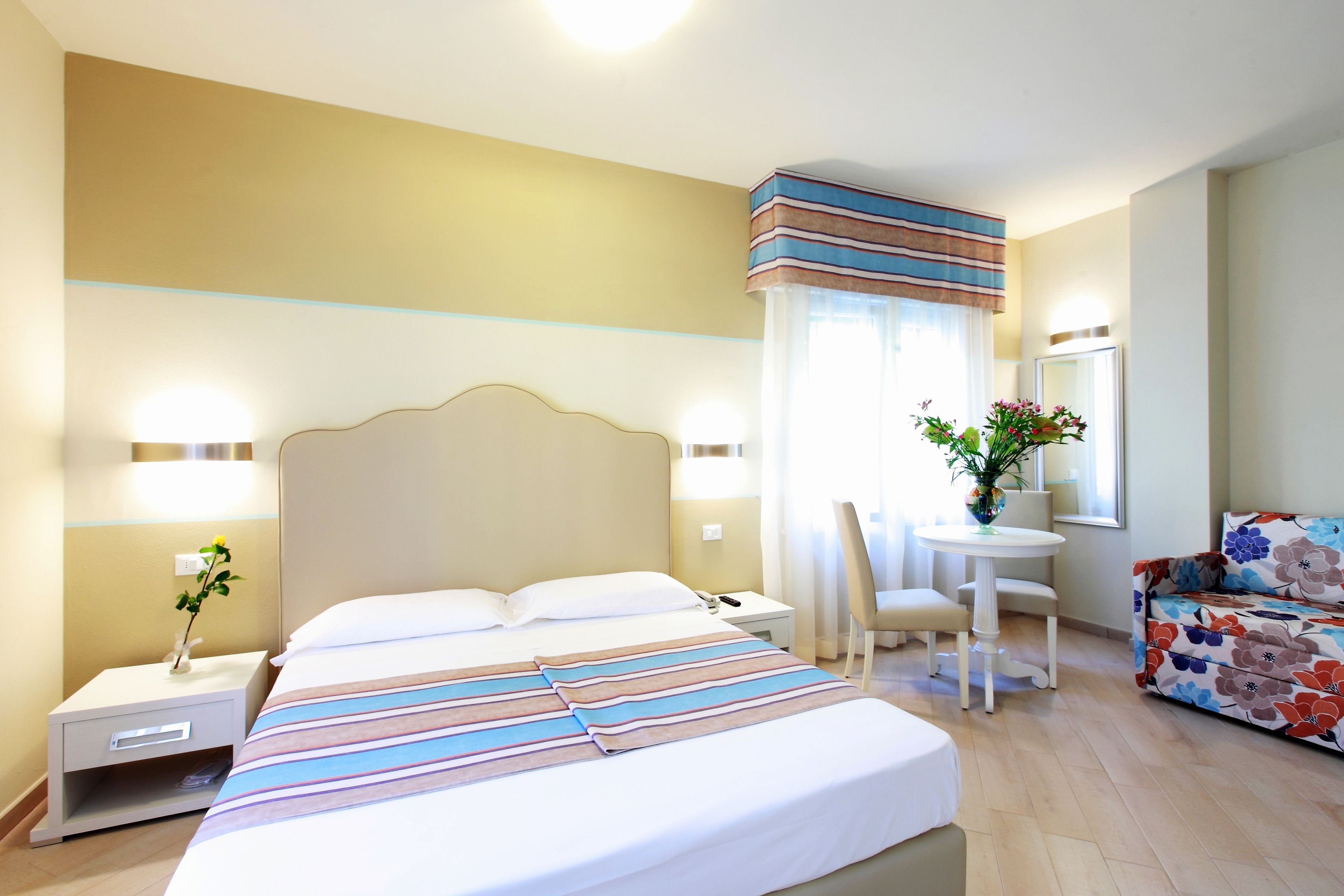A hotel room with a large bed, bedside tables, a desk, and a chair.