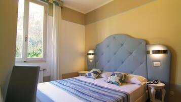Une chambre à coucher avec un lit, une table de chevet, une chaise et une fenêtre avec des rideaux.