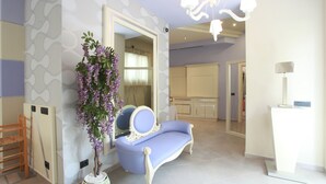 Una habitación con un sofá azul, una silla de madera, una planta en maceta y un espejo.