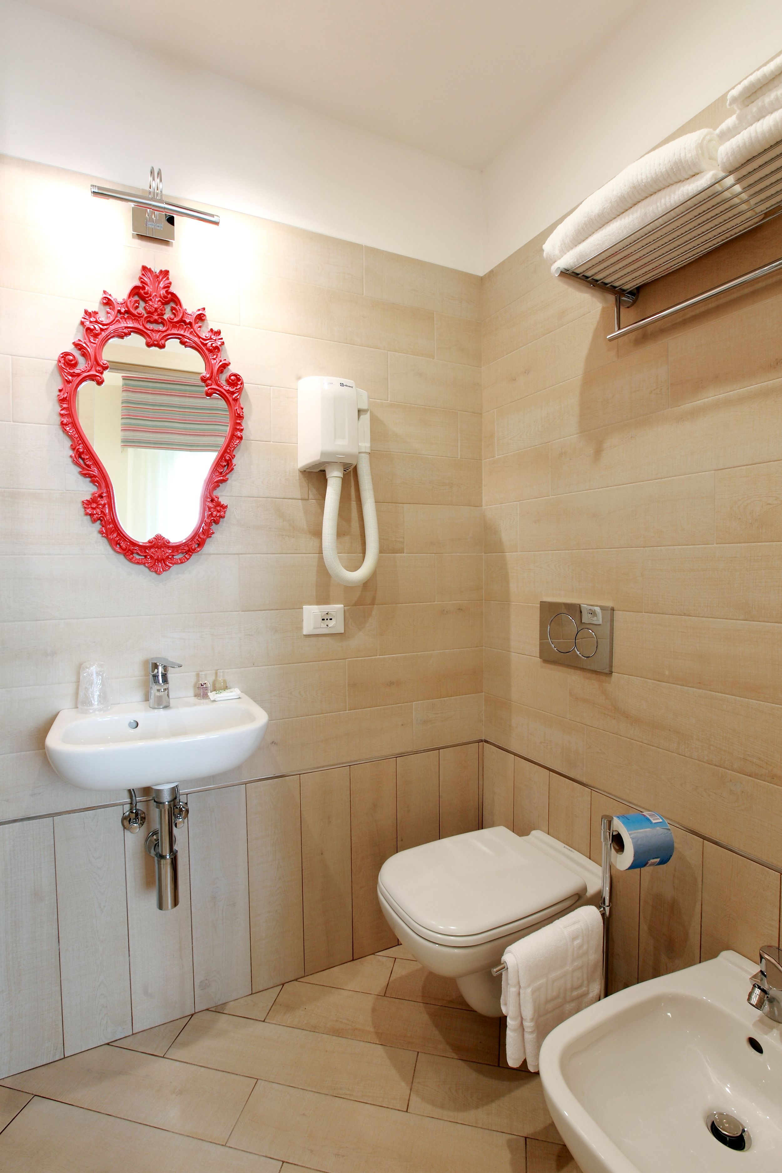A bathroom with a sink, toilet, and a mirror with a red frame.