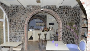 Una habitación con paredes de piedra, una zona de bar, sillas transparentes y un sofá azul.