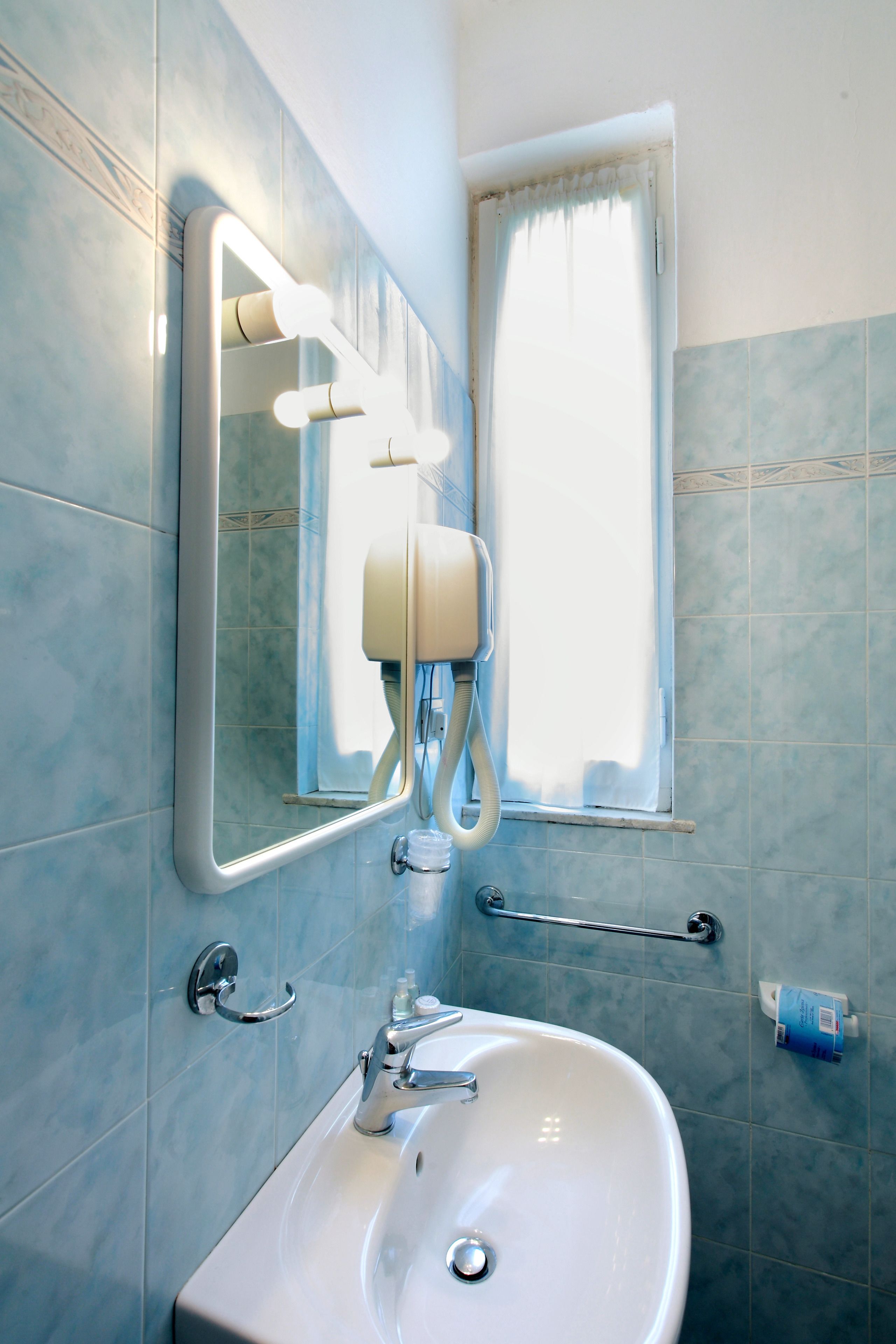 A bathroom with a sink, mirror, and handrails.