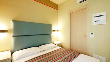 Ein Hotelzimmer mit Bett, Nachttisch, Lampe und Klimaanlage.
