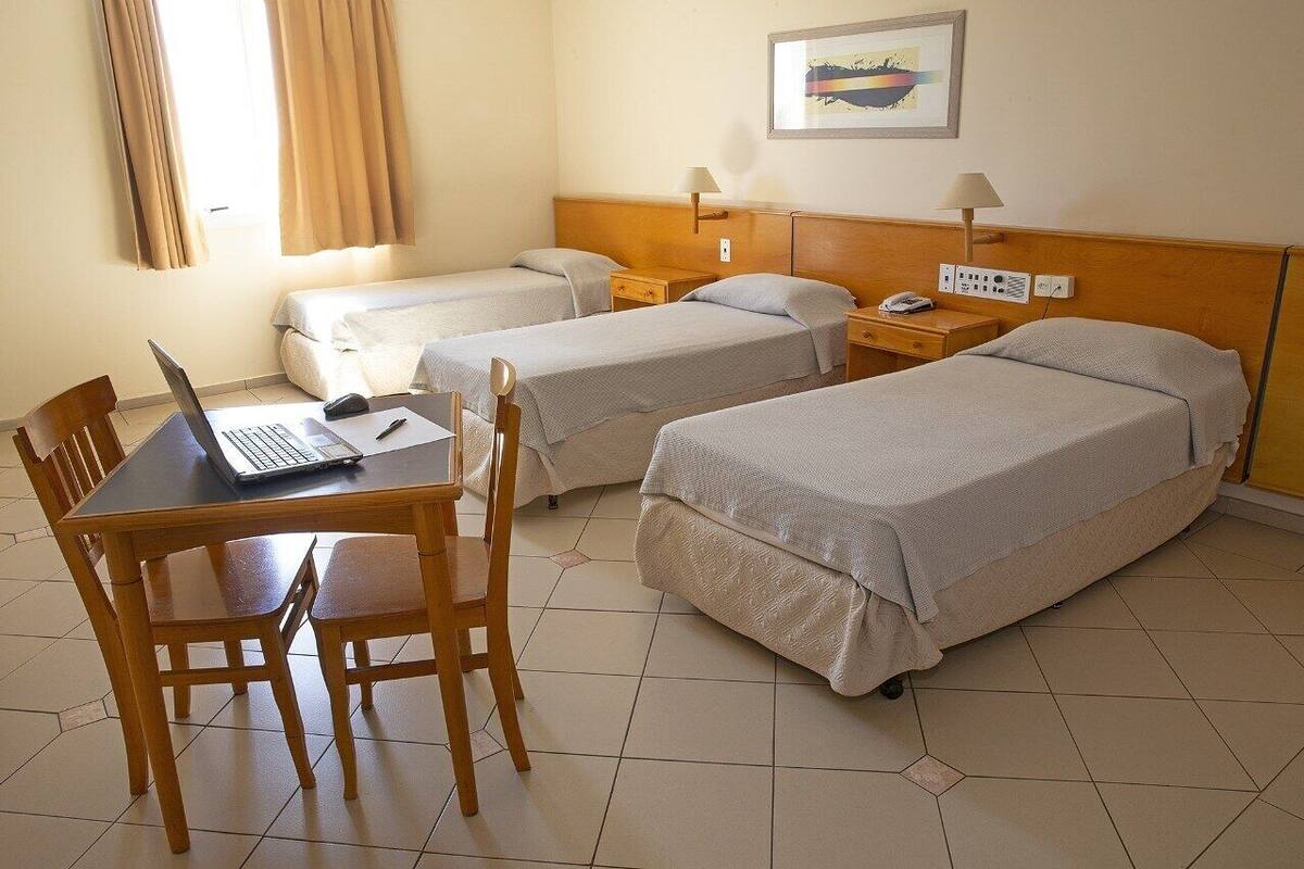 Una habitación de hotel con dos camas individuales, un escritorio con una computadora portátil y una silla.