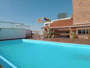 Una piscina al aire libre, sillones reclinables de piscina