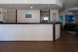 Welcome to our reception area, featuring a central desk with a unique panel design and a cozy seating area with a sofa and table.