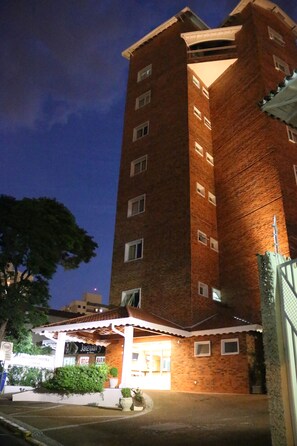 Experience the Jaguar Hotel's elegant entrance, featuring a beautifully landscaped garden and a striking brick facade.