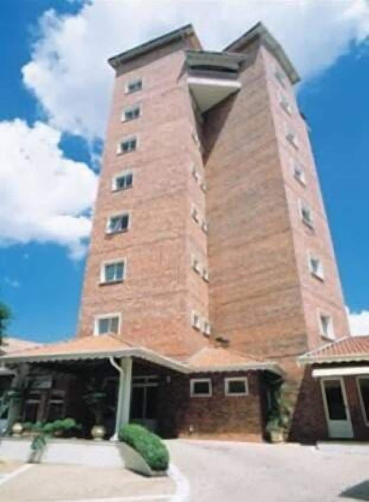 Un edificio alto de ladrillo con múltiples ventanas y techo plano.