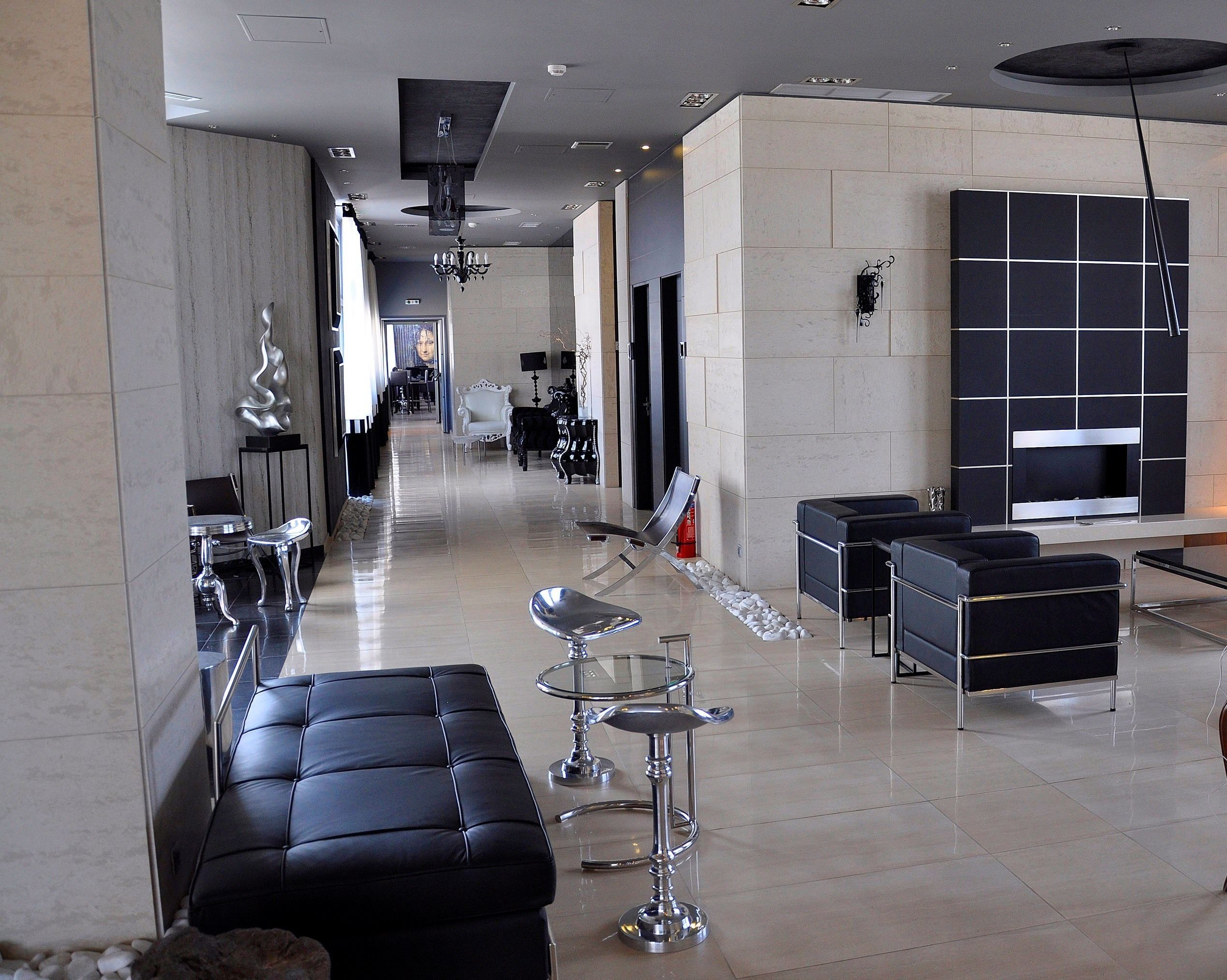 Eine moderne Hotelhalle mit einer langen Rezeption, schwarzen Ledersesseln, einer Glasbar und einer großen schwarz-weißen Wand aus Fliesen.