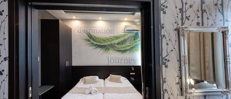 A bedroom with a large bed, a mirror, and a wall with a floral pattern.