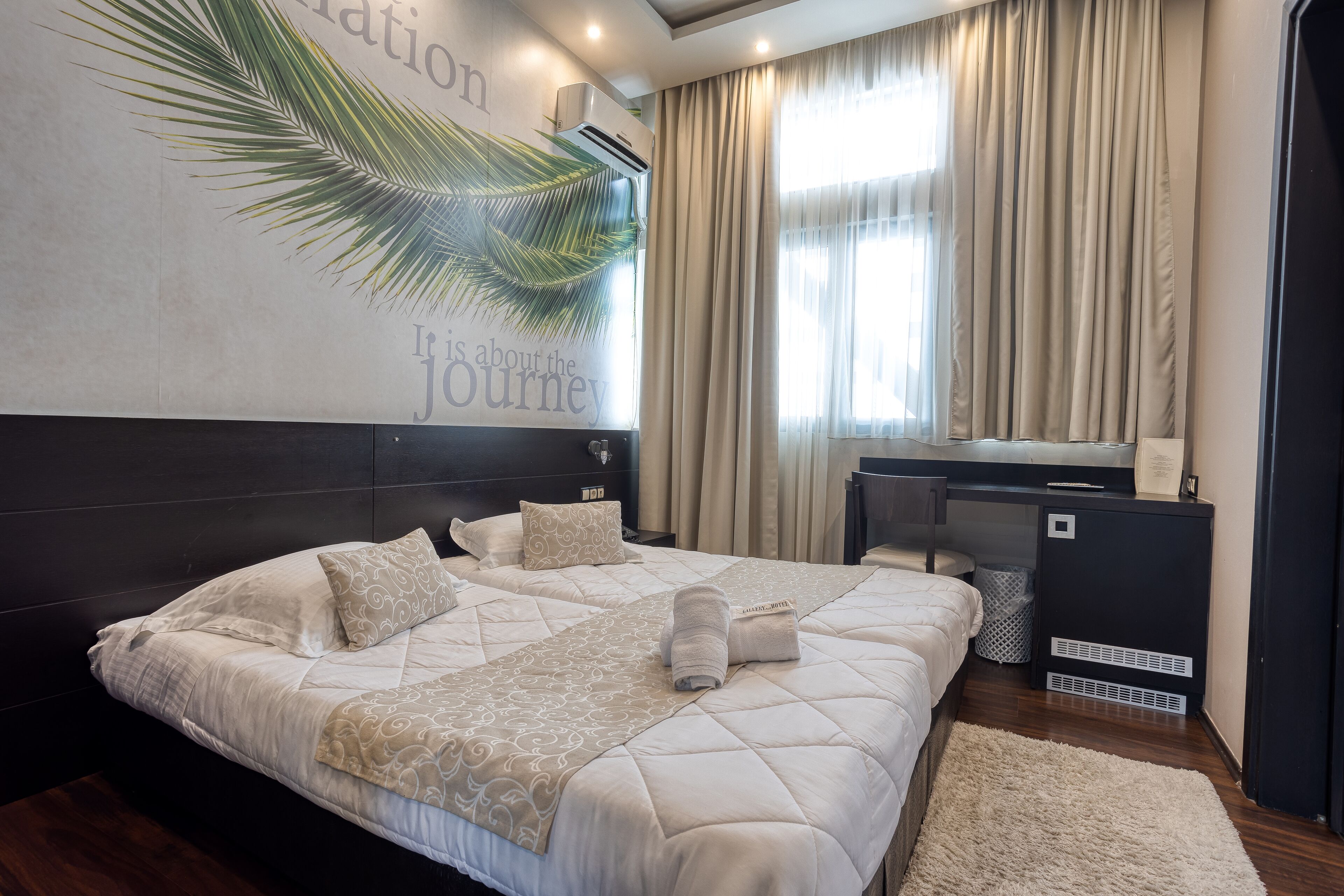 A modern hotel room with a large bed, a desk, and a wall-mounted air conditioner.