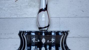 A black and white ornate dresser with a vase of branches against a tiled wall.