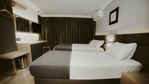 Une chambre d’hôtel avec deux lits, un bureau, une chaise, une télévision et un appareil de climatisation.