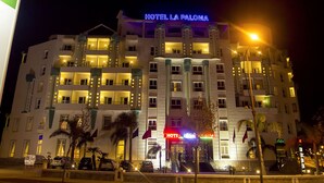 Un hotel a più piani con insegne illuminate, balconi e un ingresso ben illuminato.